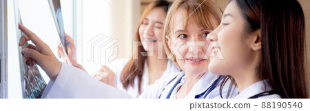 Group of team doctors examining x-ray film about skull and skeleton of patient for checking disease. 88190540