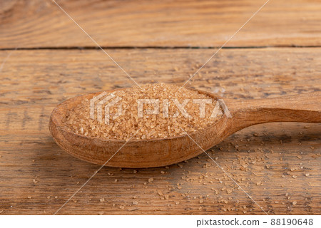Close-up of a wooden spoon with cane sugar on a wooden table. 88190648