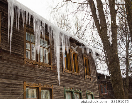 Frozen transparent icicles hang on the edge of the roof. Frozen transparent icicles hang on the edge of the roof. 88191075