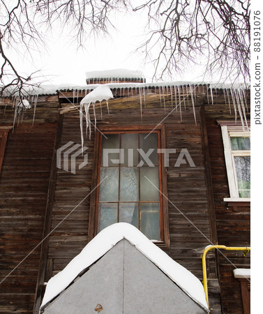 Winter transparent icicles hang on the edge of the roof. 88191076