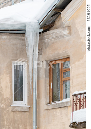 Fabulous ice icicles hang from a drainpipe at the edge of the roof. Fabulous ice icicles hang from a drainpipe at the edge of the roof. 88191095