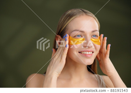 Close up of blonde caucasian girl face with natural no makeup look and white smile. Silicone under eye patches. Using skincare products from dark circles. Close up of blonde caucasian girl face with natural no makeup look and white smile. Silicone under eye patches. Using skincare products from dark circles. 88191543