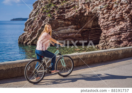 Woman tourist on a bicycle explores Budva in Montenegro. Cycling in Montenegro concept 88191737