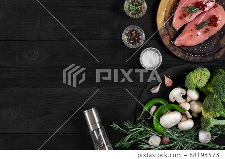 Raw chicken breast fillets on wooden cutting board with herbs and spices. Top view with copy space Raw chicken breast fillets on wooden cutting board with herbs and spices. Top view with copy space 88193573