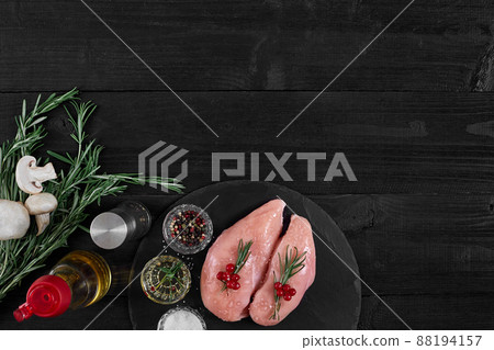 Chicken breast on a cutting board with herbs and different vegetables on rustic wooden background. 88194157