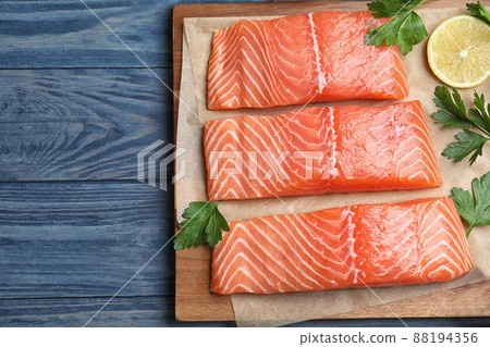 Top view of fresh raw salmon with parsley on blue wooden table. Fish delicacy 88194356