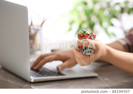Woman squeezing colorful slime in office, closeup. Antistress toy 88194507
