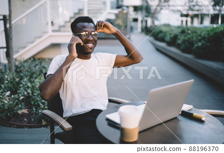 Positive african american male in eyewear having fun making call Positive african american male in eyewear having fun making call 88196370
