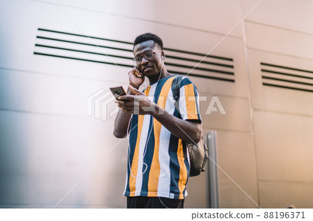 African American casual guy listening to music in modern city African American casual guy listening to music in modern city 88196371