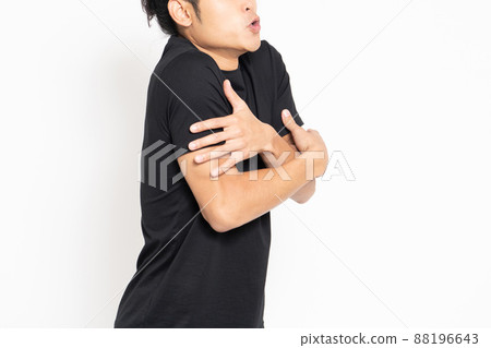 A man wearing a black T-shirt standing in front of a white background and posing unwell 88196643