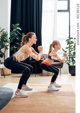 Home training. Mother and daughter doing squats Home training. Mother and daughter doing squats 88198329