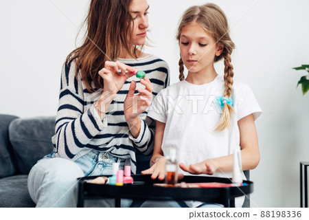 Mother and daughter doing manicure at home, painting nails with nail polish 88198336