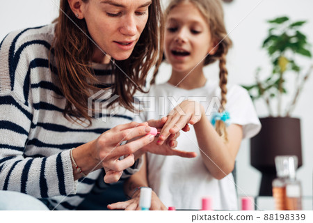 Mother and daughter doing manicure at home, painting nails with nail polish 88198339