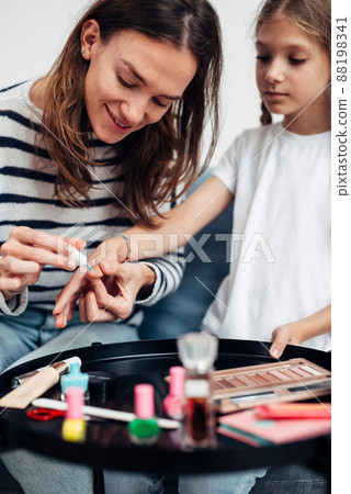 Mother and daughter doing manicure at home, painting nails with nail polish 88198341