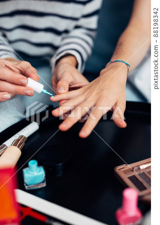 Mother and daughter doing manicure at home, painting nails with nail polish. 88198342