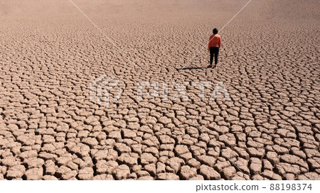 Silhouette of a man on a sandy cracked empty not fertile land during a drought. The concept of ecological catastrophe on the planet. 88198374