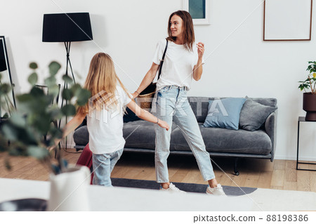 Mother and daughter with a suitcase looking around the new apartment Mother and daughter with a suitcase looking around the new apartment 88198386