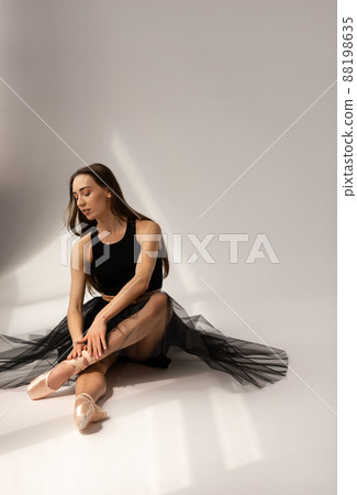Beautiful ballerina sitting on floor and touching legs. 88198635