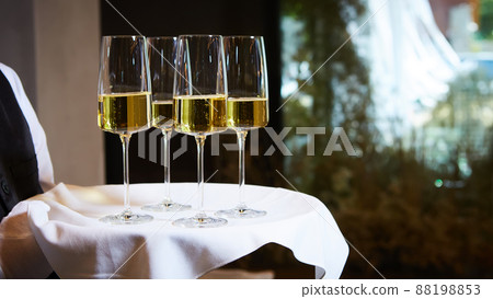 The waiter carries glasses with cold champagne. 88198853