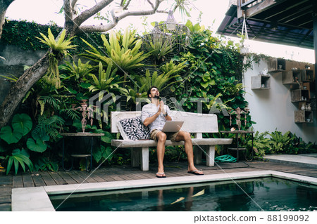 Anxious man with laptop praying for luck in tropical resort Anxious man with laptop praying for luck in tropical resort 88199092