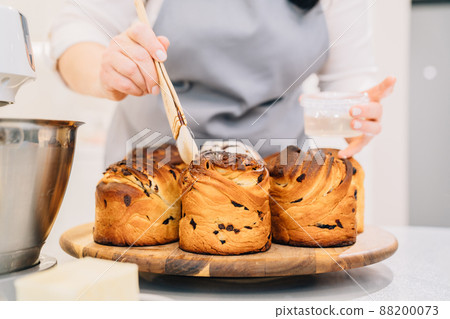 a female cook lubricates with melted butter a Kraffin, easter cake a female cook lubricates with melted butter a Kraffin, easter cake 88200073