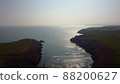 Atlantic Ocean cliffs with sun glare in drone flight over Stradbally Cove, Cooper Coast, Waterford, Ireland. 88200627