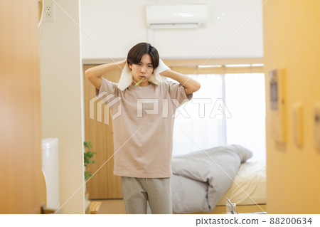 Young man drying his hair while brushing his teeth 88200634