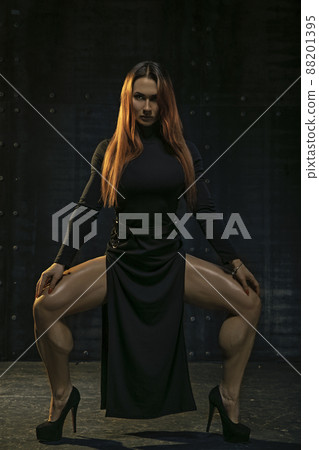 Attractive red-haired girl in black dress demonstrates athletic legs 88201395