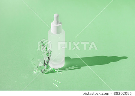 Serum skincare product with collagen and peptide in white bottle with dropper on green backdrop with crystal glass prism refracting light effects and rays of light. Product mockup packaging Serum skincare product with collagen and peptide in white bottle with dropper on green backdrop with crystal glass prism refracting light effects and rays of light. Product mockup packaging 88202095