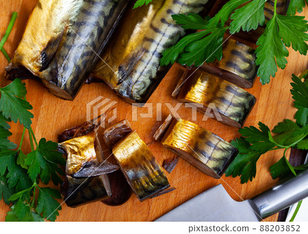 Smoked mackerel cut into pieces with parsley on a table 88203852