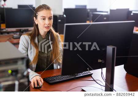 Female teacher working on computer in library university Female teacher working on computer in library university 88203942
