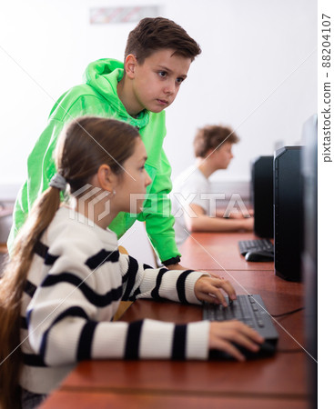 Preteen schoolboy helping girl classmate during informatics lesson Preteen schoolboy helping girl classmate during informatics lesson 88204107