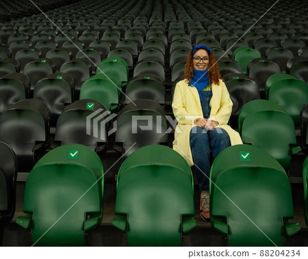 Caucasian woman cheers for a sports team at the stadium. The girl watches the match at the stadium alone. 88204234