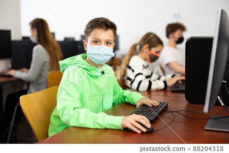 Young boy in mask using computer during lesson Young boy in mask using computer during lesson 88204318