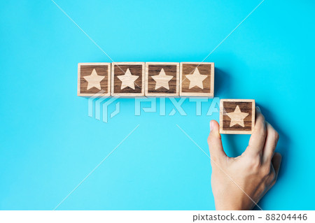 hand holding Star block on blue background. Customer choose rating for user reviews. Service rating, ranking, customer review, satisfaction, evaluation and feedback concept hand holding Star block on blue background. Customer choose rating for user reviews. Service rating, ranking, customer review, satisfaction, evaluation and feedback concept 88204446