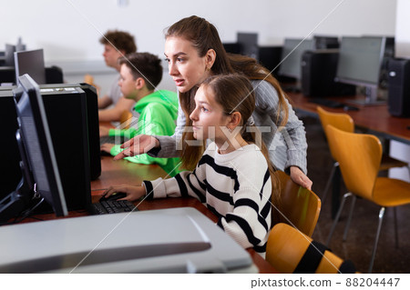 Teacher helping girl to solve computer problem Teacher helping girl to solve computer problem 88204447