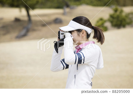 用高爾夫測距儀測量距離的高爾夫女孩 用高爾夫測距儀測量距離的高爾夫女孩 88205000