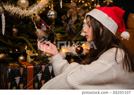 A sad teenage girl in a red Santa hat thinks about the past. A sad teenage girl in a red Santa hat thinks about the past. 88205107