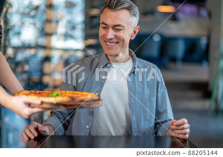 A man sitting in a cafe and getting ready for eating a delicious pizza A man sitting in a cafe and getting ready for eating a delicious pizza 88205144