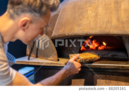 A man making fire in the oven in italian bakery 88205161