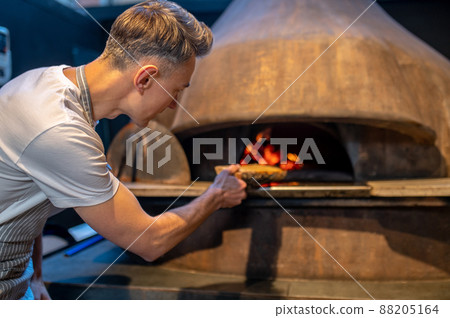A man making fire in the oven in italian bakery 88205164