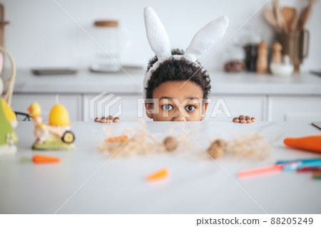 Cute girl wuth bunny ears in the kitchen smiling happily Cute girl wuth bunny ears in the kitchen smiling happily 88205249