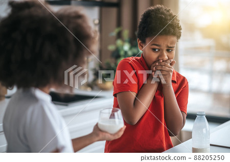 A boy in red shirt refusing from milk A boy in red shirt refusing from milk 88205250