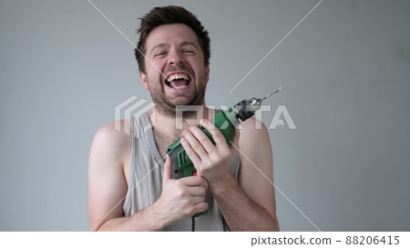 Crazy young man going mad doing repair holding drill in hands. Crazy young man going mad doing repair holding drill in hands. 88206415