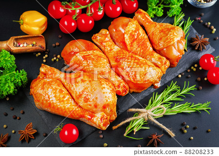 Convenience food, precooked.Raw Marinated chicken meat legs with spices for cooking for BBQ dark background. Top view. 88208233