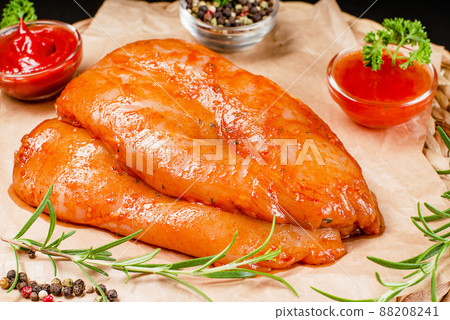 Marinated chicken fillet in red sauce on a dark background. Raw marinated chicken fillet with fresh rosemary. Convenience food. Marinated chicken fillet in red sauce on a dark background. Raw marinated chicken fillet with fresh rosemary. Convenience food. 88208241