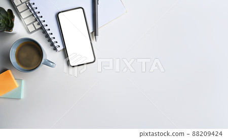 Mobile phone with blank screen, coffee cup and notebook on white table with copy space. Mobile phone with blank screen, coffee cup and notebook on white table with copy space. 88209424