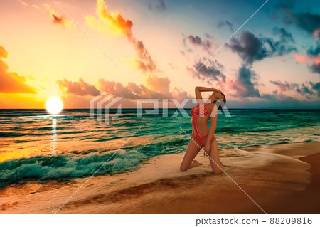 紅色背景中的白色在海中以雙膝跪地的姿勢，在夕陽的波浪中擠壓身體，色彩豐富，透明度高 88209816