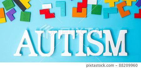 AUTISM text with colorful wood puzzle pieces, geometric shape block on blue background. Concepts of health, Autistic Spectrum disorder and world Autism awareness day 88209960