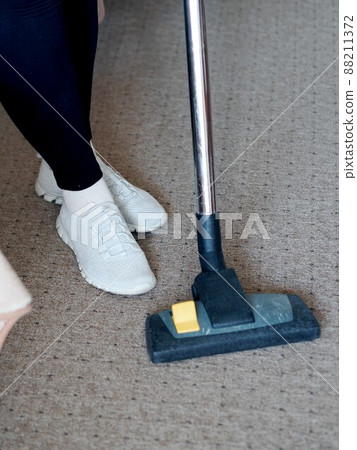 Cleaning the room with a vacuum cleaner. Close-up of legs and a brush on the floor. Cleaning the room with a vacuum cleaner. Close-up of legs and a brush on the floor. 88211372